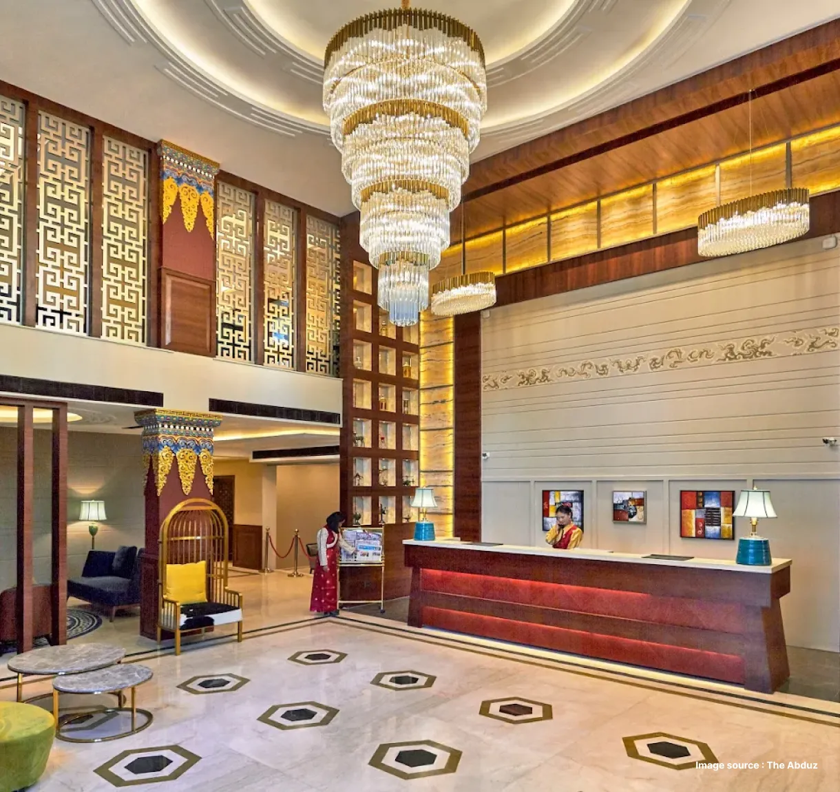 a hotel reception with a large chandelier and golden accents