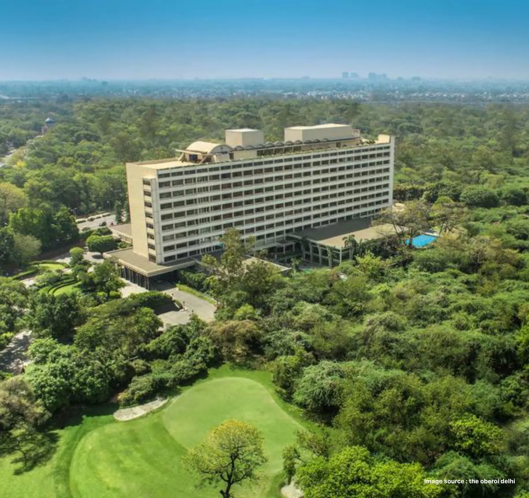 aerial shot of the grand oberoi hotel building in delhi, surrounded by green jungles