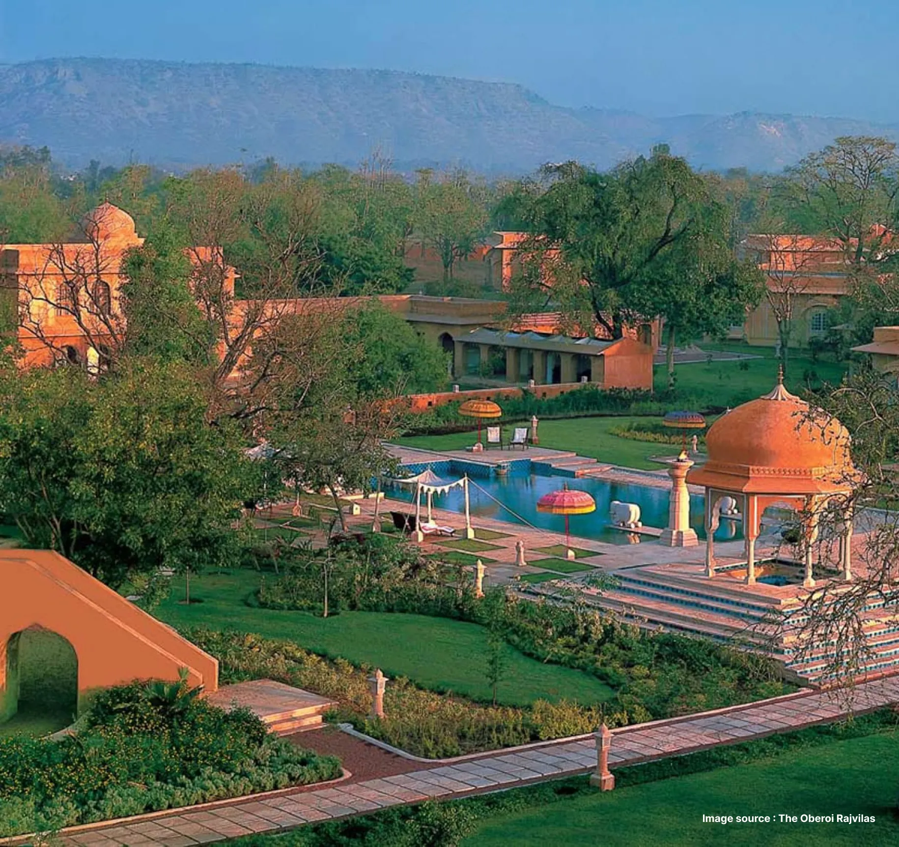lush green gardens of the oberoi rajvilas hotel in jaipur with pool view and beautiful dome structures