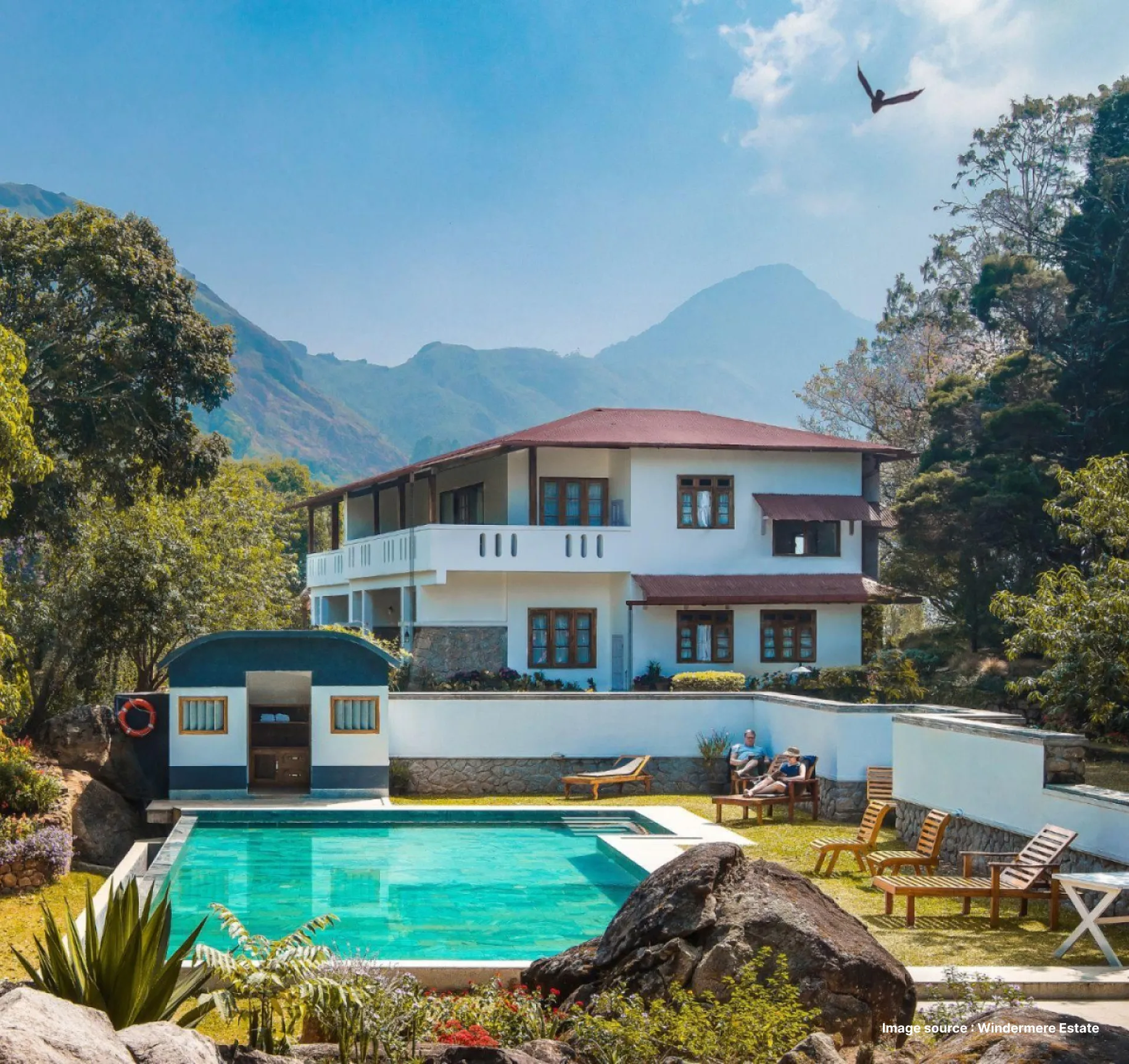 pool area view of the windermere estate with a 2 storey cottage style stay in the background with mountains and trees