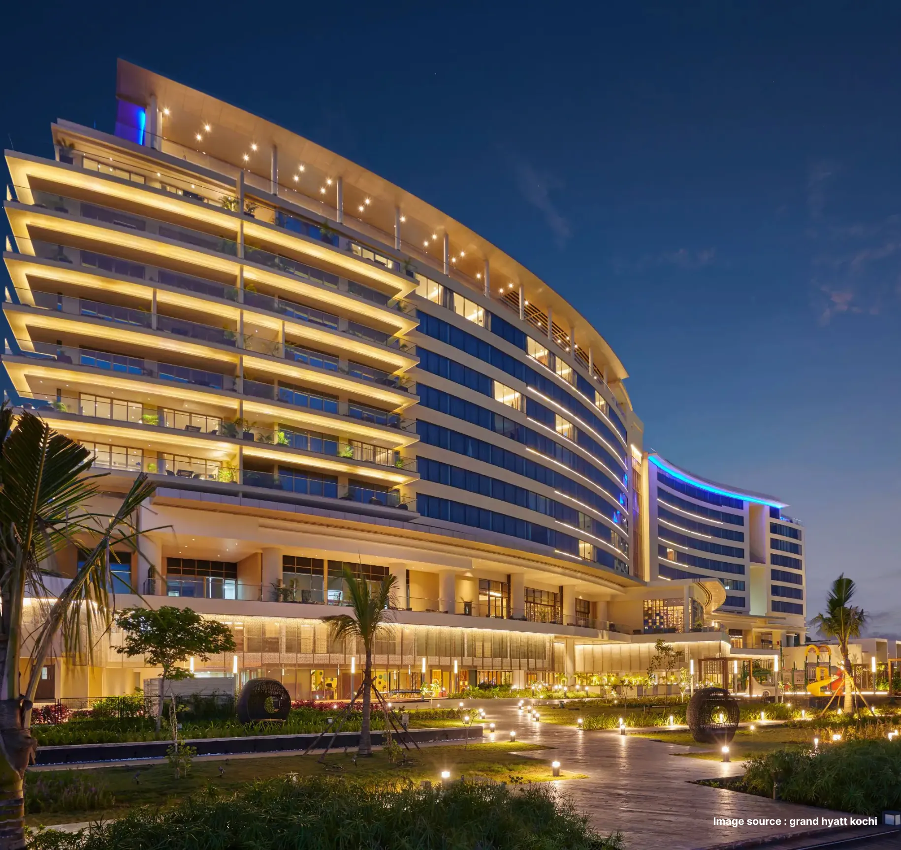 night view of the lit up grand hyatt hotel in kochi with modern architecture