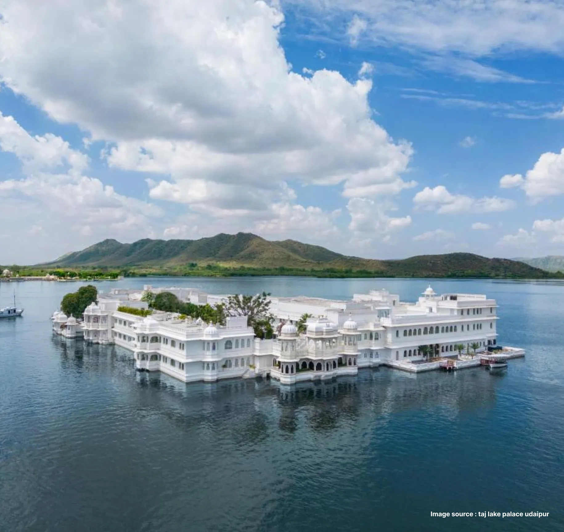 aerial shot of the taj lake palace in udaipur - an ethereal white building floating in the middle of the lake