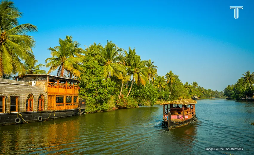 A peaceful houseboat drifts through Kerala's lush backwaters under a golden sunset - women travel