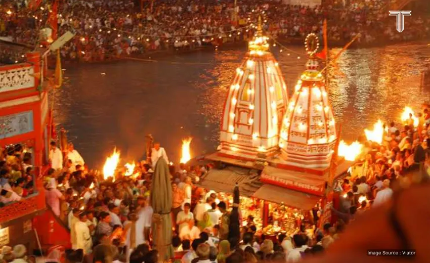 A luxurious private riverboat with teakwood decks and white canopies glides serenely on the calm, golden-hued waters of the Ganges at sunset in ganga river cruise.
